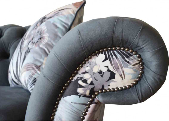 Ein auffälliges Dreisitzer-Sofa im Chesterfield-Design mit zarter grauer Blumendekoration